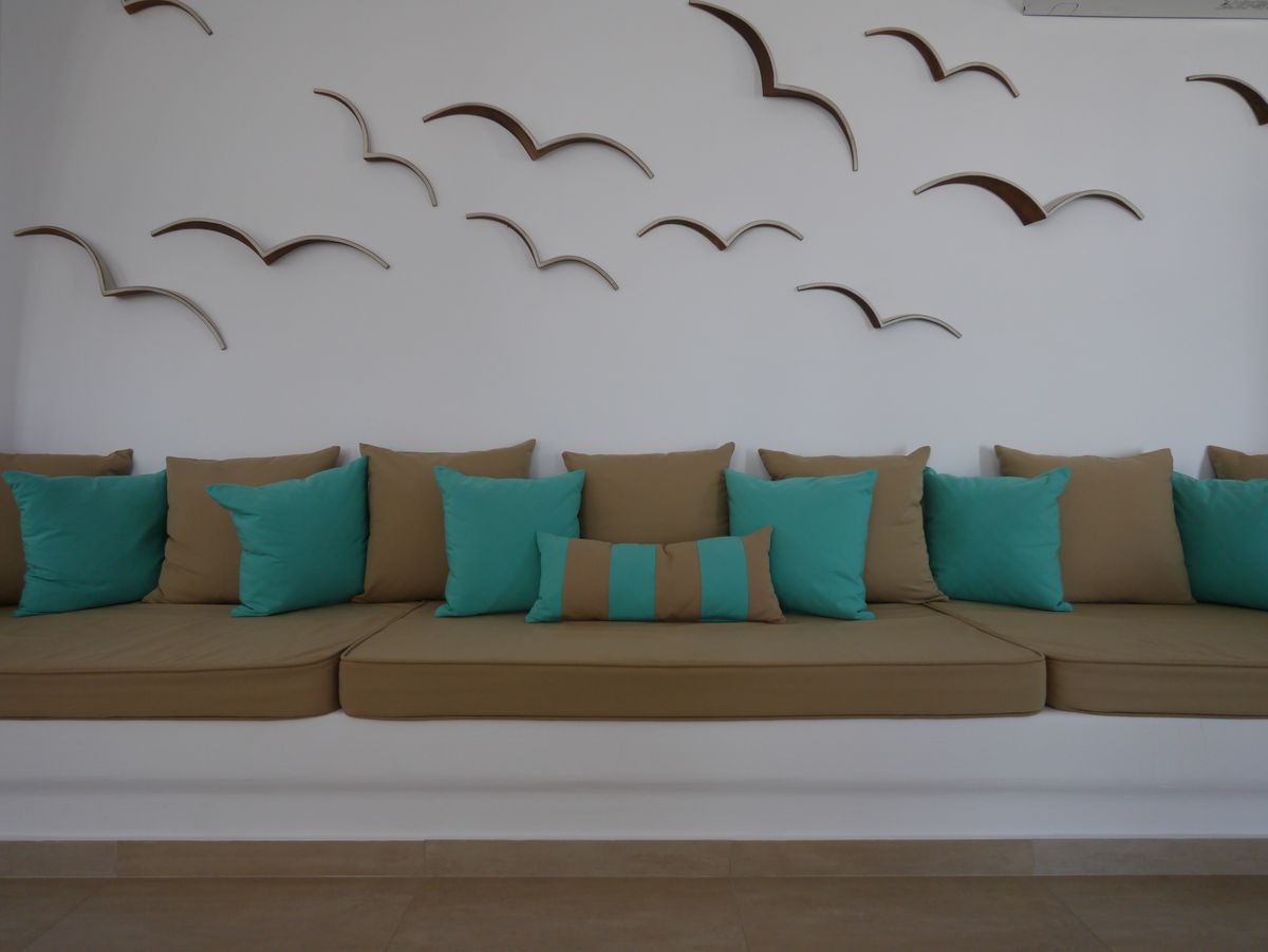 Modern minimalist sofa with teal and tan pillows, and bird wall decor.