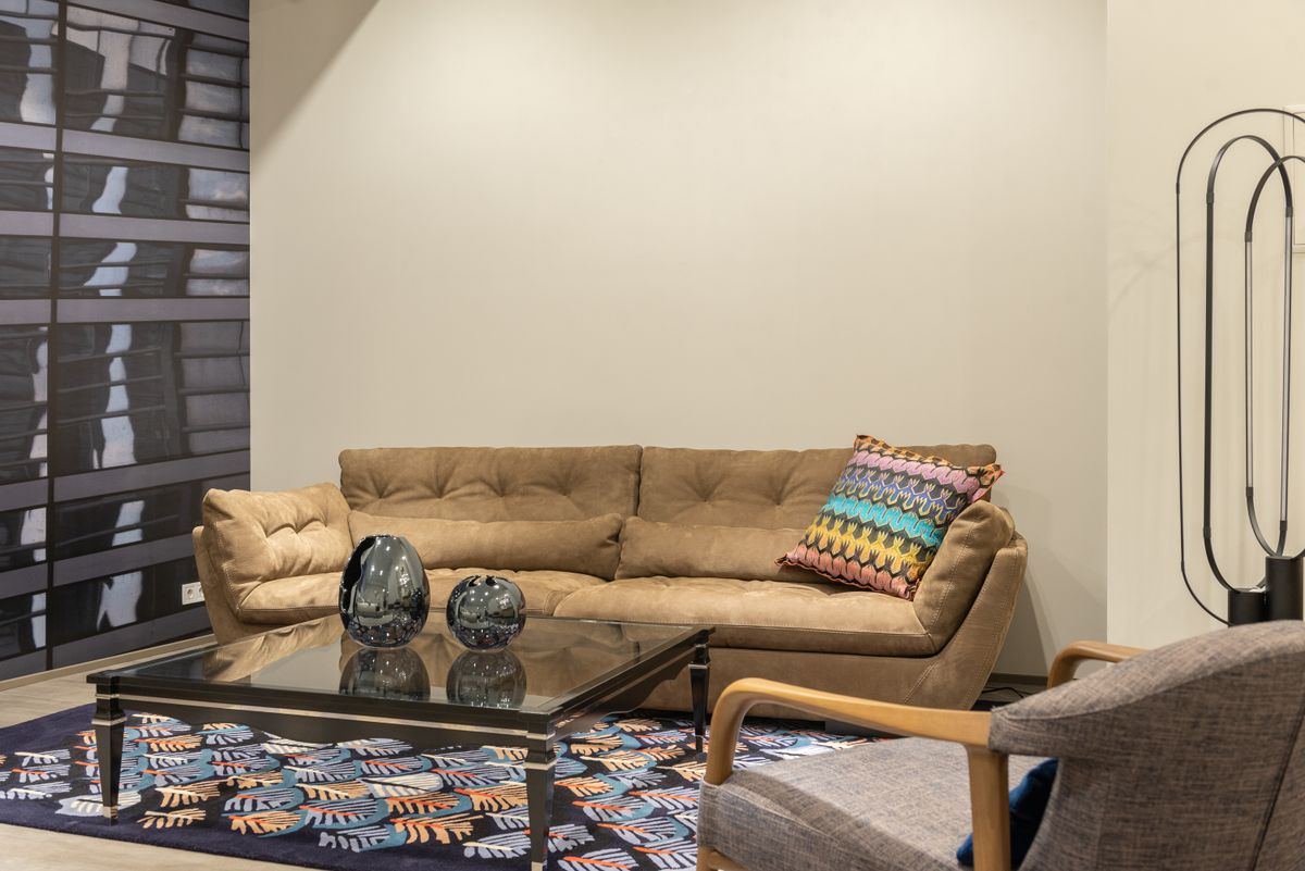 Interior of modern living room with comfortable sofa with colorful cushion and table on carpet near armchair