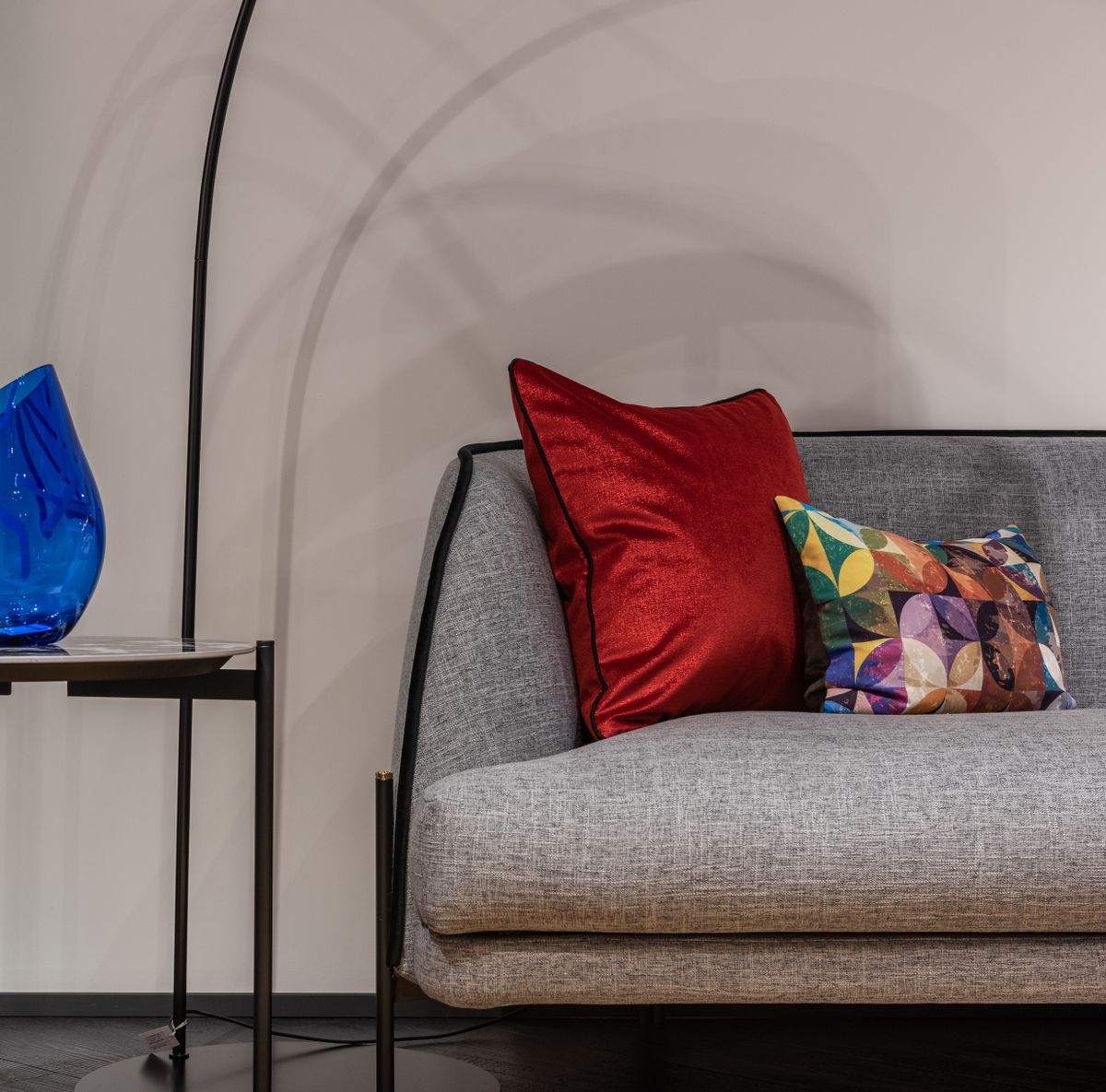 Comfortable gray couch with colorful cushions placed at wall near small side table in modern living room of contemporary apartment