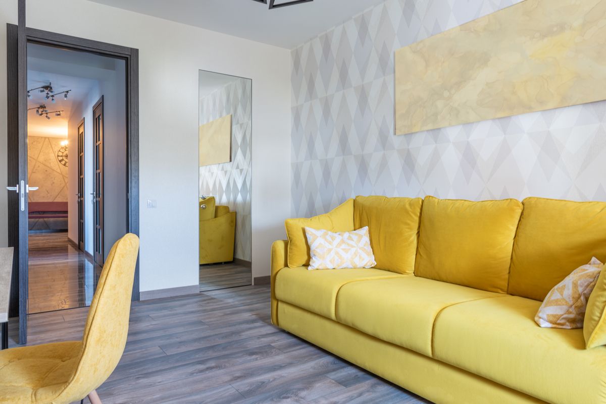 Modern living room interior with couch under decorative panel against chair and door in light house