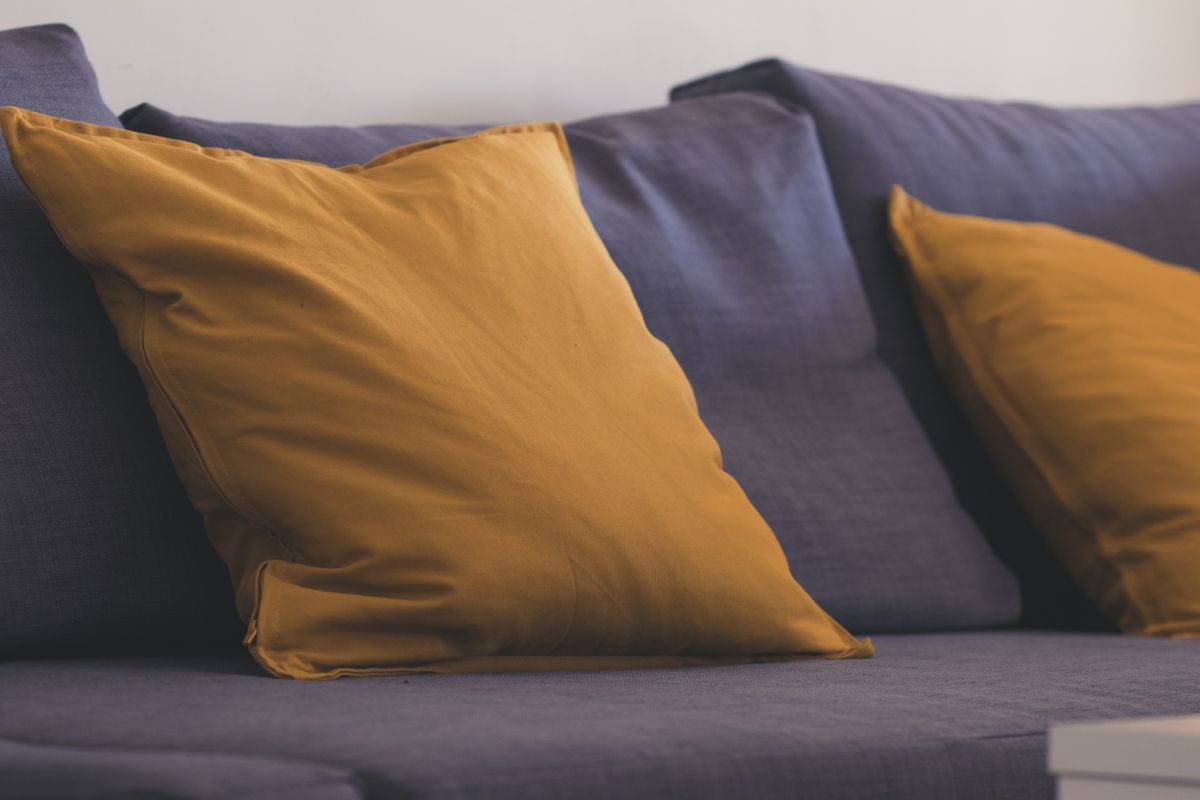Comfortable blue sofa with vibrant yellow throw pillows in a stylish interior setting.