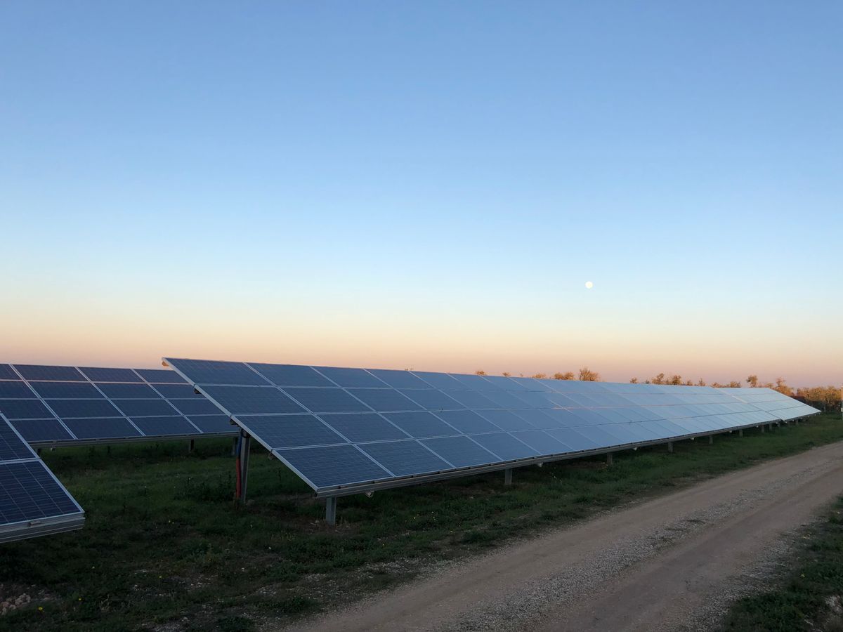 Solar panels in a field at dusk near Andria, Italy, capturing renewable energy.