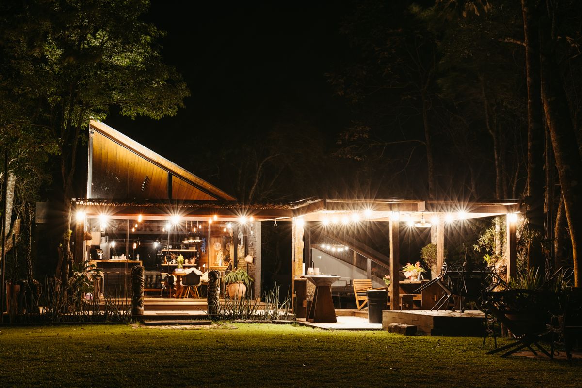 Cozy outdoor dining setting illuminated by warm lights on a summer night in Santa Teresa, Brazil.