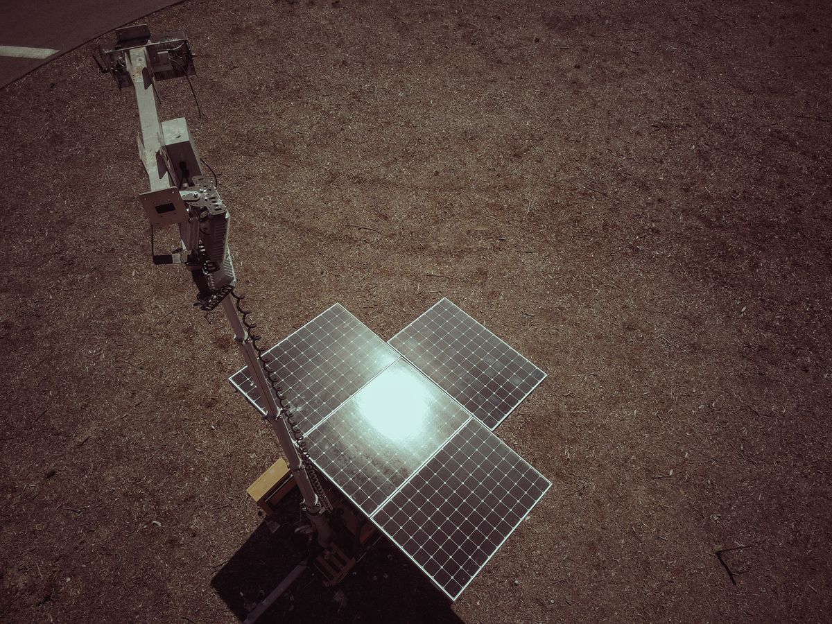 Aerial shot of a solar panel on a deserted landscape, reflecting sunlight.
