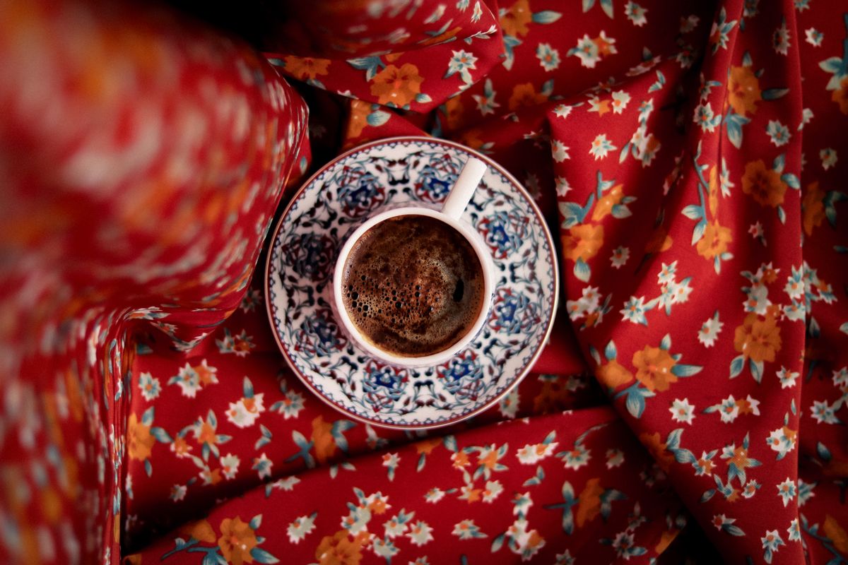 Top view of a patterned coffee cup on vibrant red floral fabric.