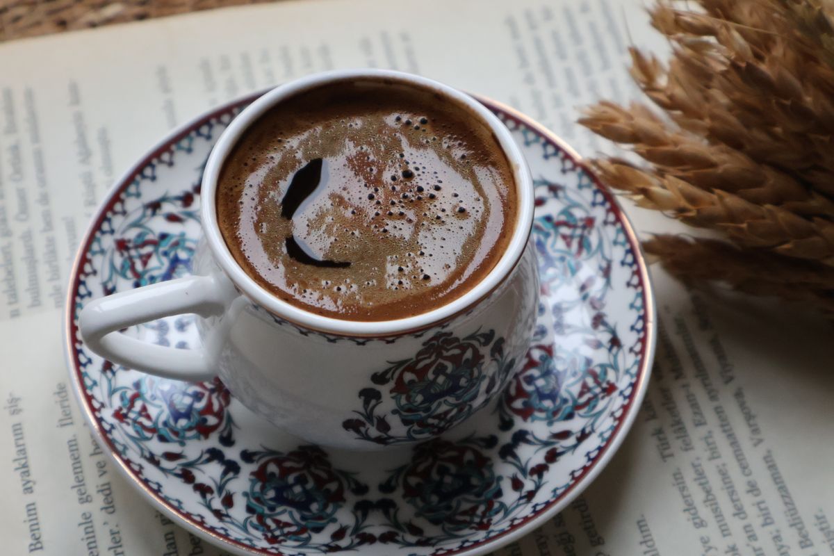 A beautifully crafted Turkish coffee in a traditional ceramic cup with floral patterns, featuring wheat decoration.