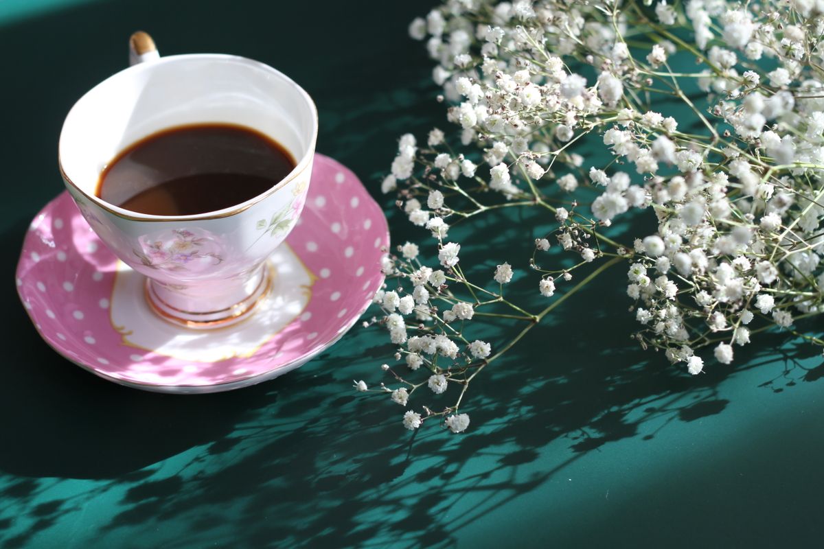 Charming coffee cup beside delicate white flowers in a serene setting, perfect for a relaxed mood.
