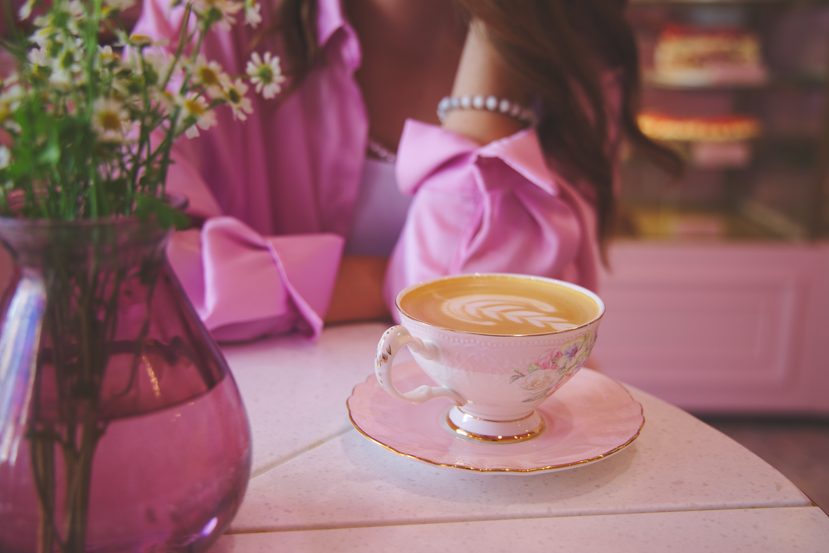 Delicate latte art in a floral cup next to daisies on a table in Kyiv, Ukraine.