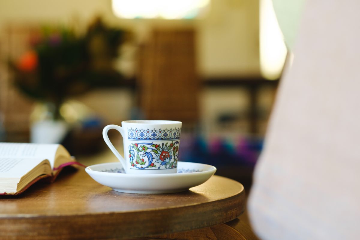 A colorful floral printed mug on a saucer on a wooden table, creating a cozy atmosphere.