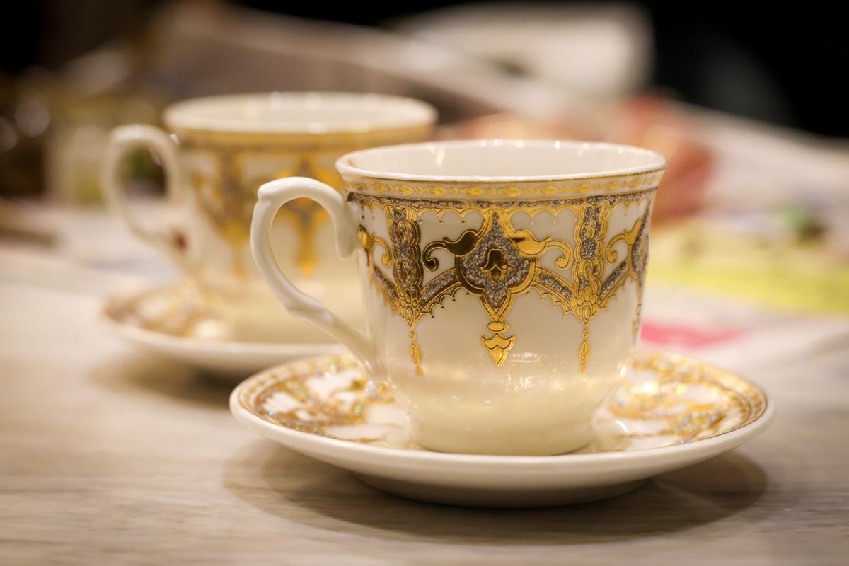 A close-up of an ornate porcelain coffee cup with intricate gold patterns in a cozy setting.