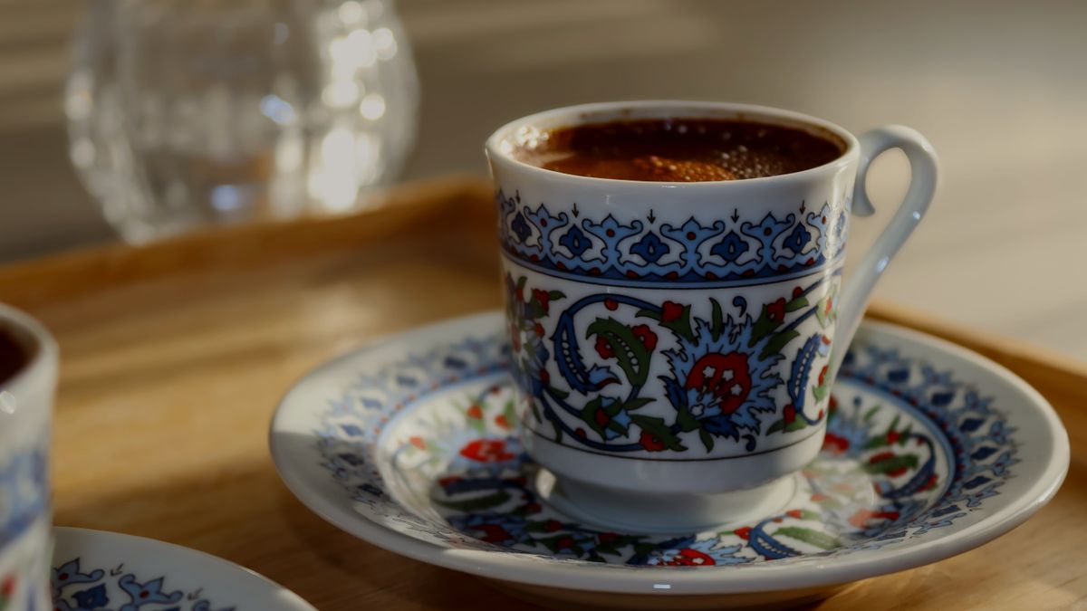 Close-up of Turkish coffee in an ornate porcelain cup on a decorative saucer.