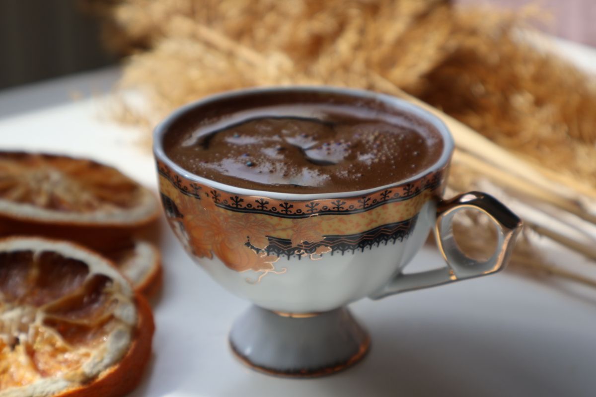An aesthetic coffee setup with rich Turkish coffee in a vintage porcelain cup, accompanied by dried oranges.