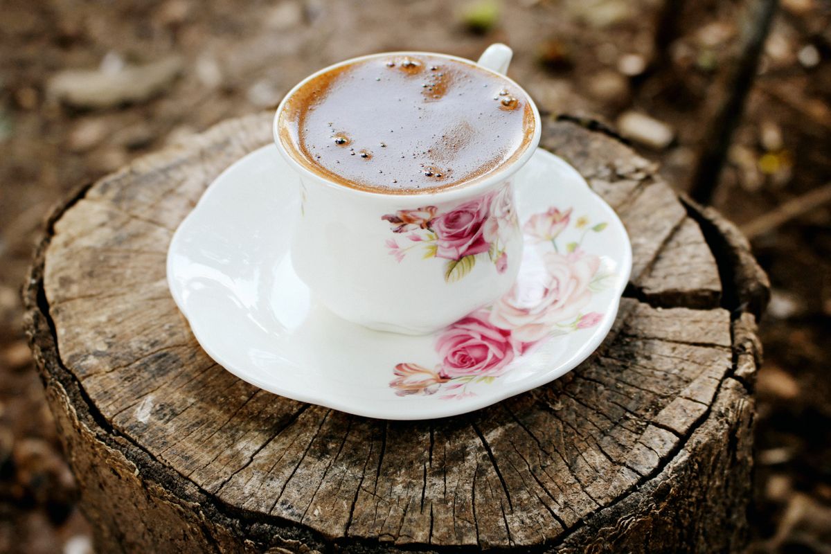 From above porcelain saucer and cup with aromatic fresh black coffee on rough rustic stub