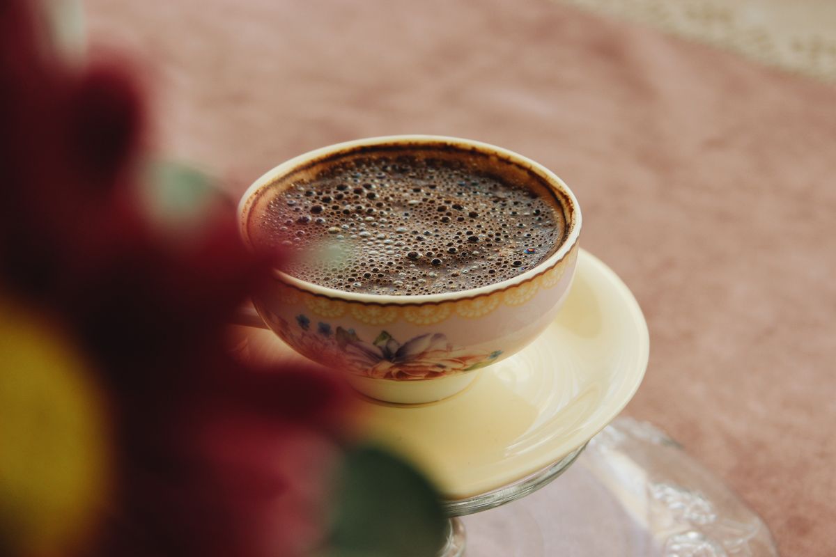 Close-up of a coffee cup with rich foam, served on a saucer, creating a cozy indoor atmosphere.