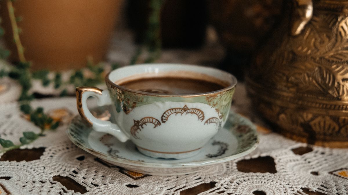 A vintage ceramic coffee cup with intricate patterns on a lace tablecloth, exuding a classic feel.