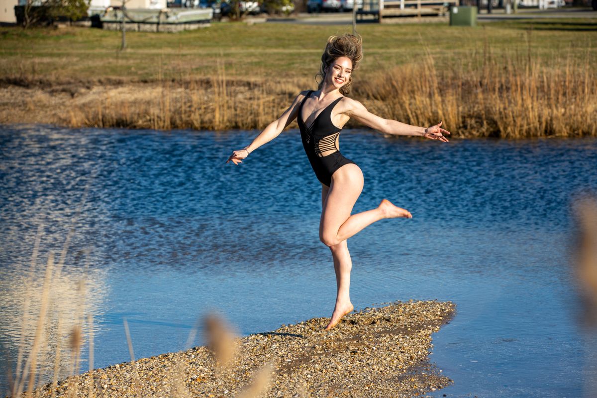 A joyful woman in a swimsuit leaps gracefully by a tranquil lake, exuding happiness and freedom.