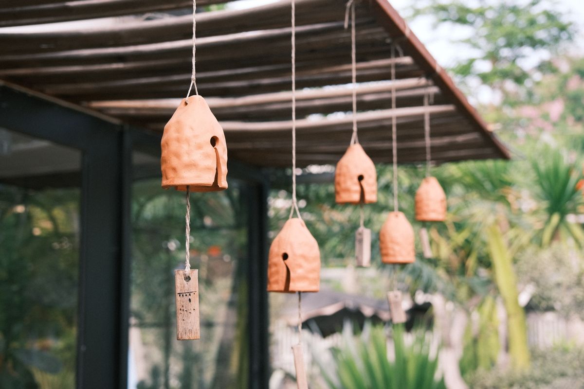 Hanging terracotta wind chimes in an outdoor garden creating a relaxing ambiance.