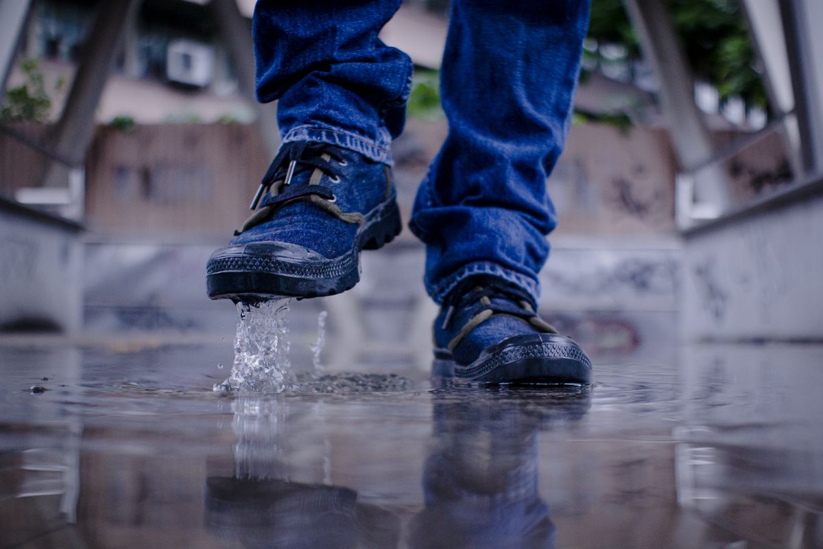 Dynamic shot of a person walking through water, creating a splash with their shoes.