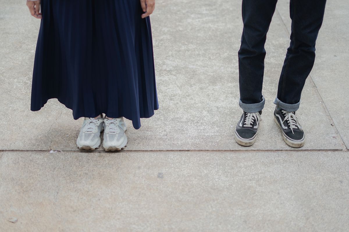 Low-angle view of a man and woman wearing sneakers and casual clothes on a street.