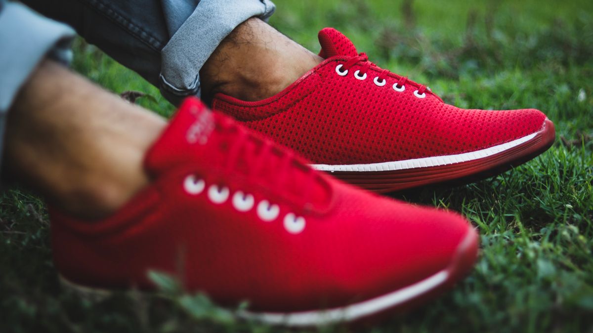 Vibrant red sneakers on green grass, showcasing casual outdoor footwear style and comfort.