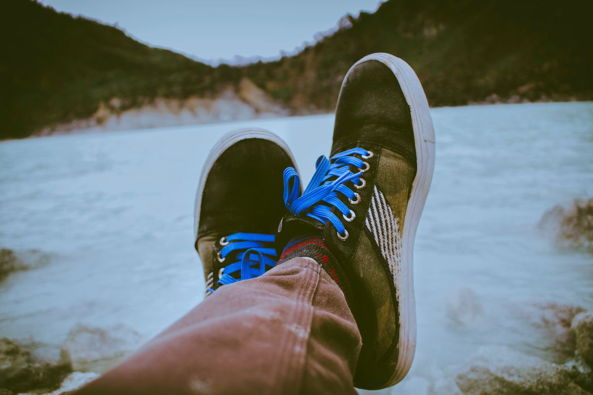 Person wearing sneakers relaxing by a scenic lake in West Java, Indonesia.