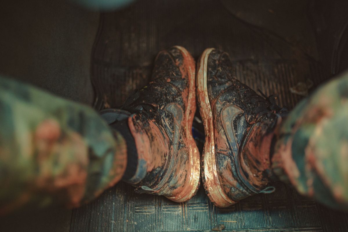 From above anonymous tourist sitting in car and showing feet in sneakers all covered with mud and clay