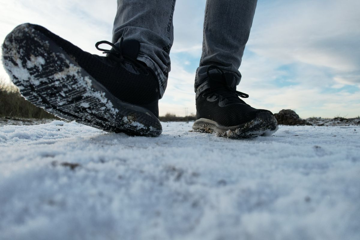 Close-up of person's feet in sneakers stepping on snowy ground in South Yorkshire.