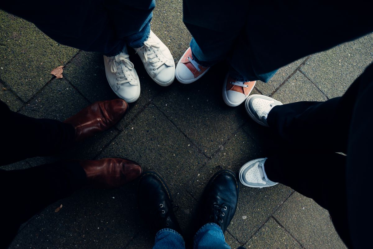 Feet in different footwear forming a circle on a street pavement. Harmony and unity concept.