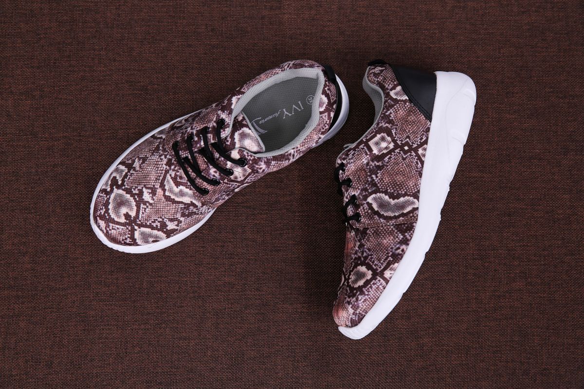 Top view of fashionable snake print sneakers on a textured brown surface, perfect for footwear fashion concepts.