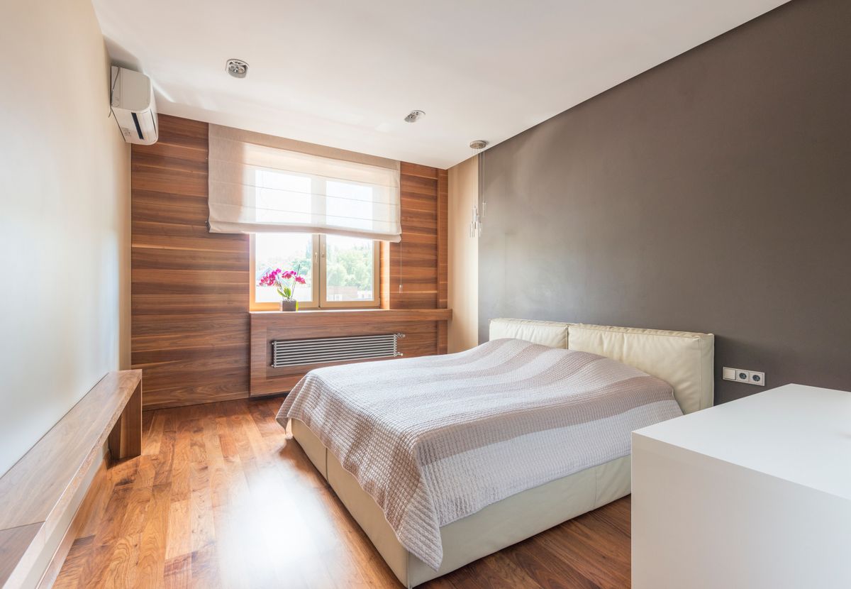 Bright and minimalist modern bedroom with wood accents and natural light through a window.