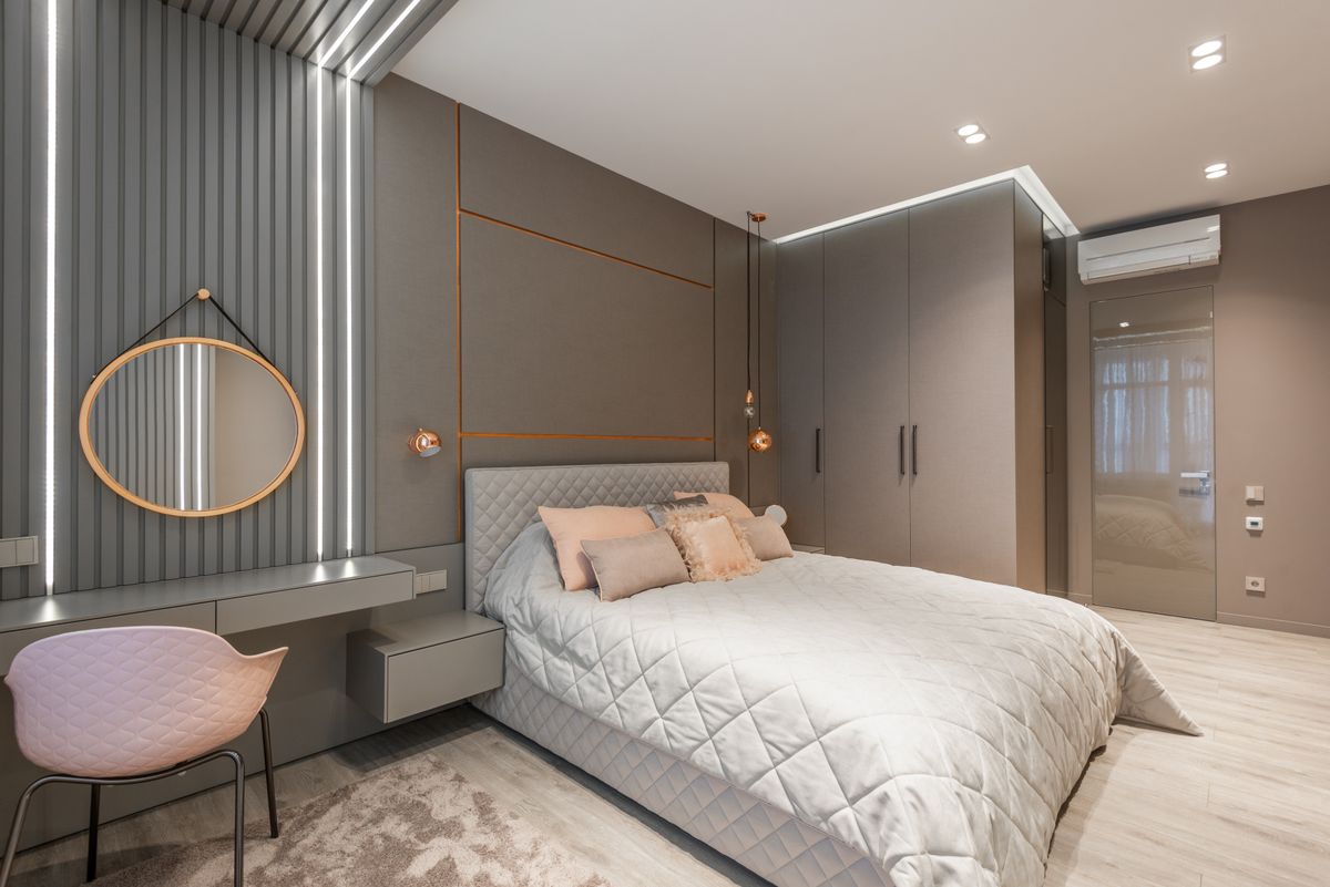 Creative design of bedroom with bed between closet and mirror reflecting lights above table at home