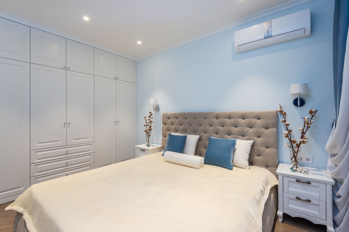 Interior of classic styled bedroom with comfy bed big wardrobe and nightstands decorated with vases with cotton plants
