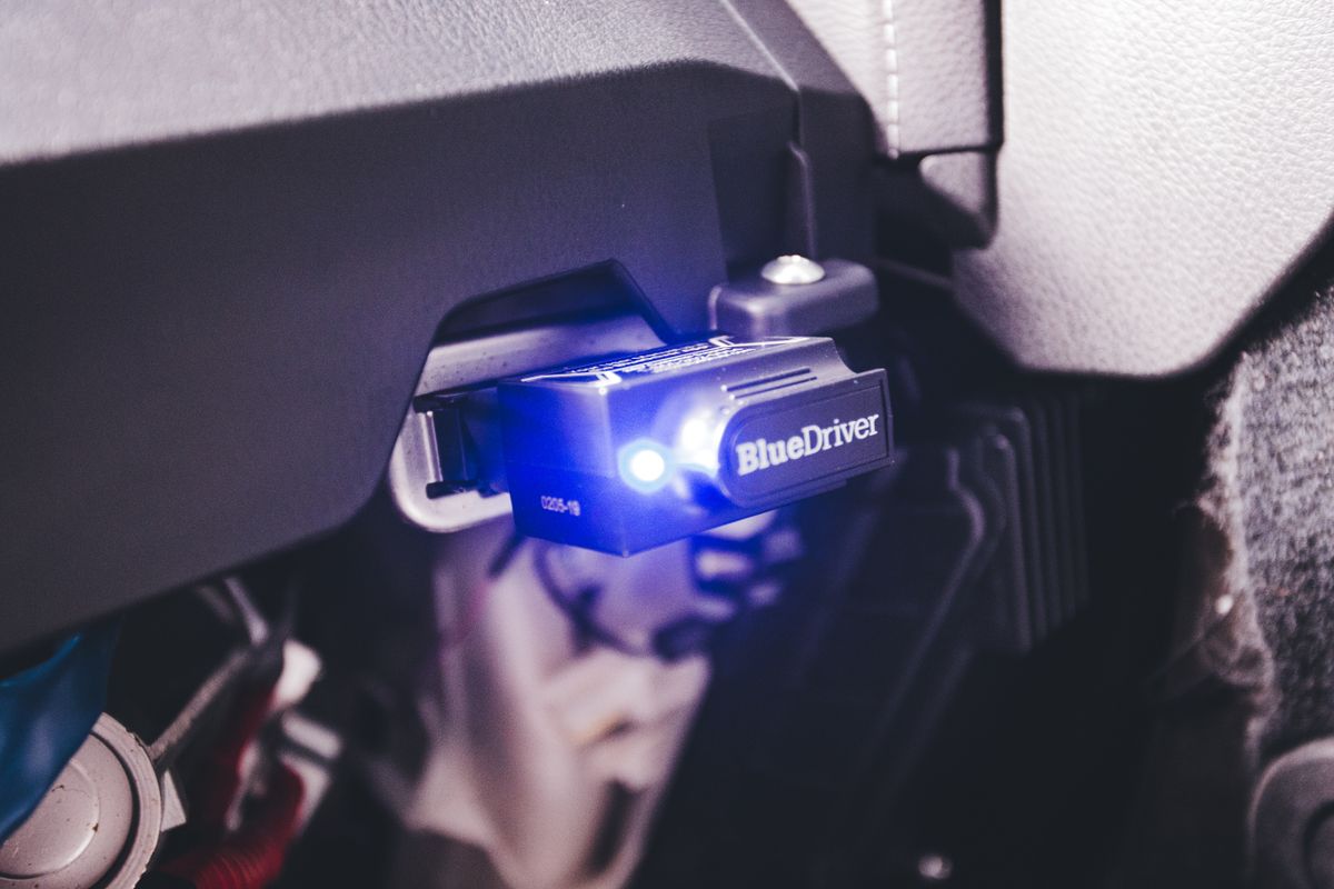 Close-up of a BlueDriver electronic car diagnostic tool plugged in a vehicle.