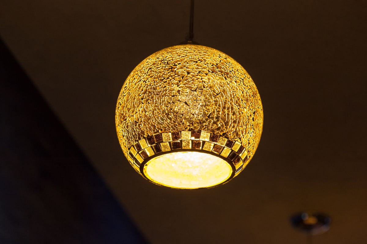 Close-up of an illuminated mosaic pendant lamp indoors, adding warmth and style to interior design.