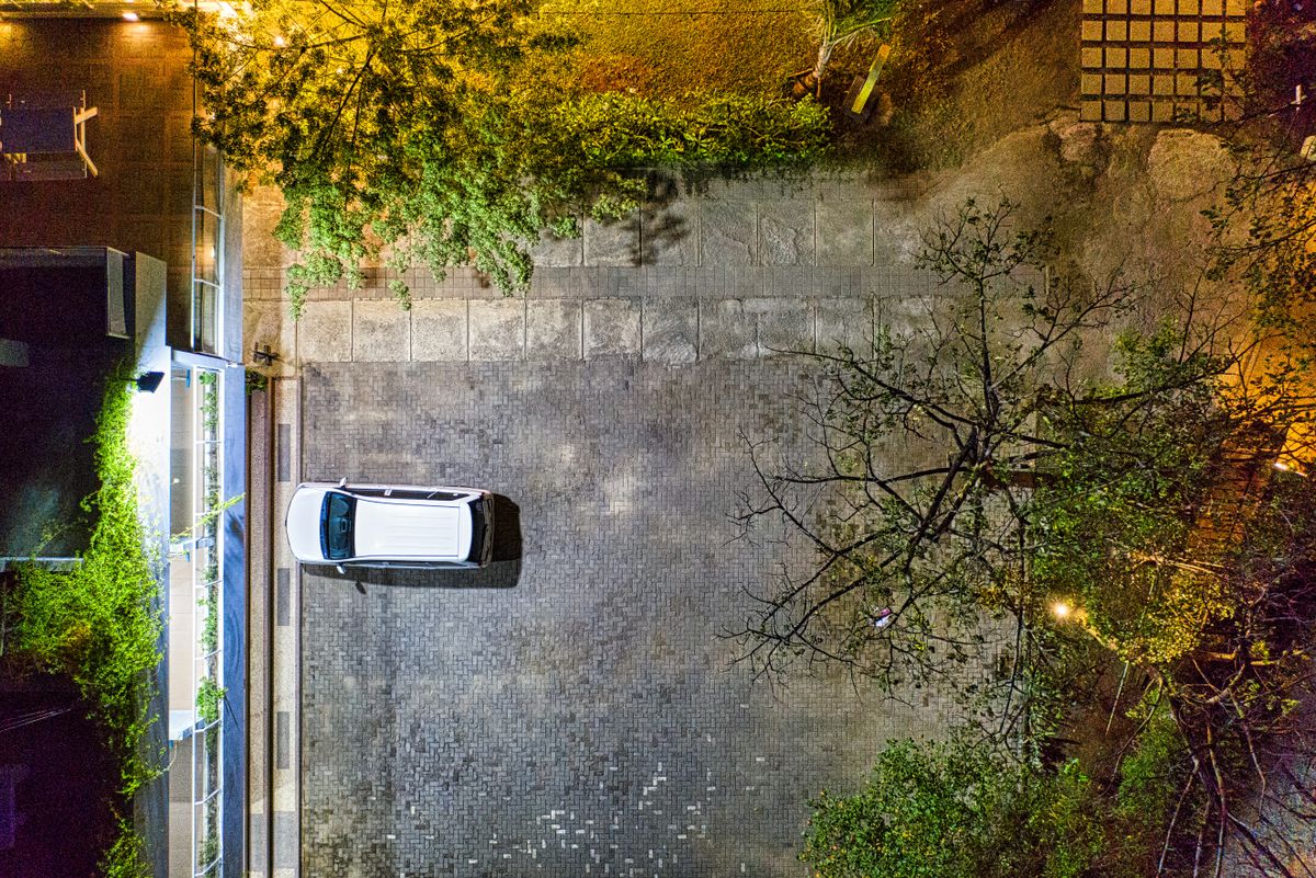 Drone view of parked transport on dry walkway against building illuminated by artificial light in town