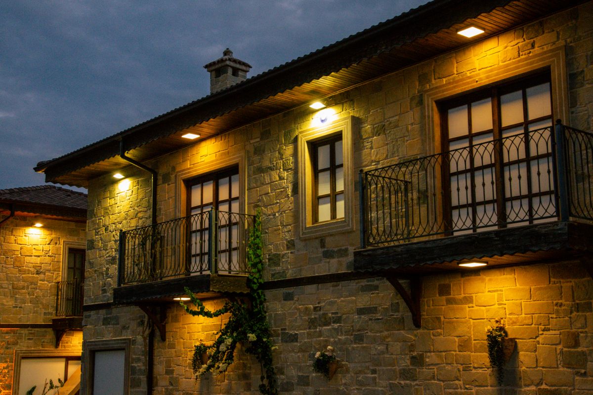 Elegant stone house with balcony and outdoor lighting at dusk in Side, Antalya.