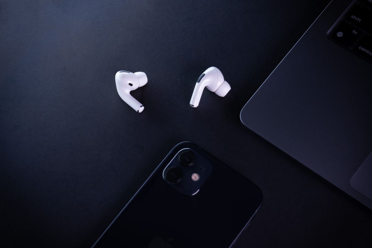 Minimalist workspace featuring earphones, smartphone, and laptop, perfect for tech lovers.