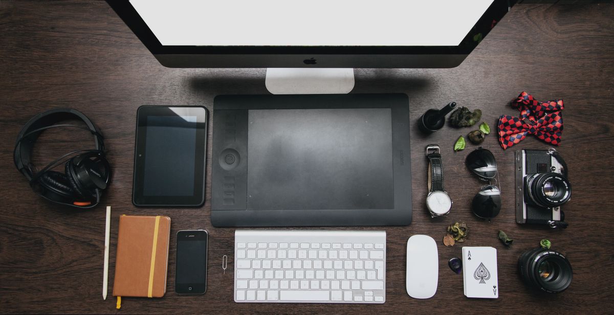 Organized workspace with tech devices and accessories on a wooden desk.