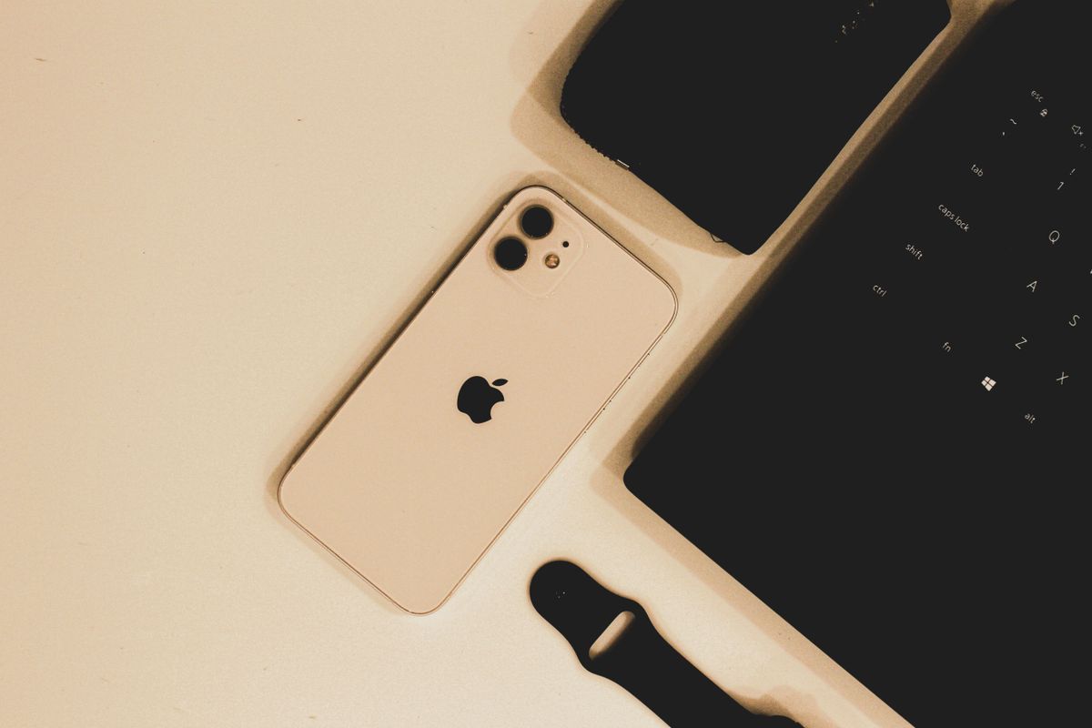 A modern desk layout featuring a smartphone, laptop, and smart watch strap, perfect for tech enthusiasts.