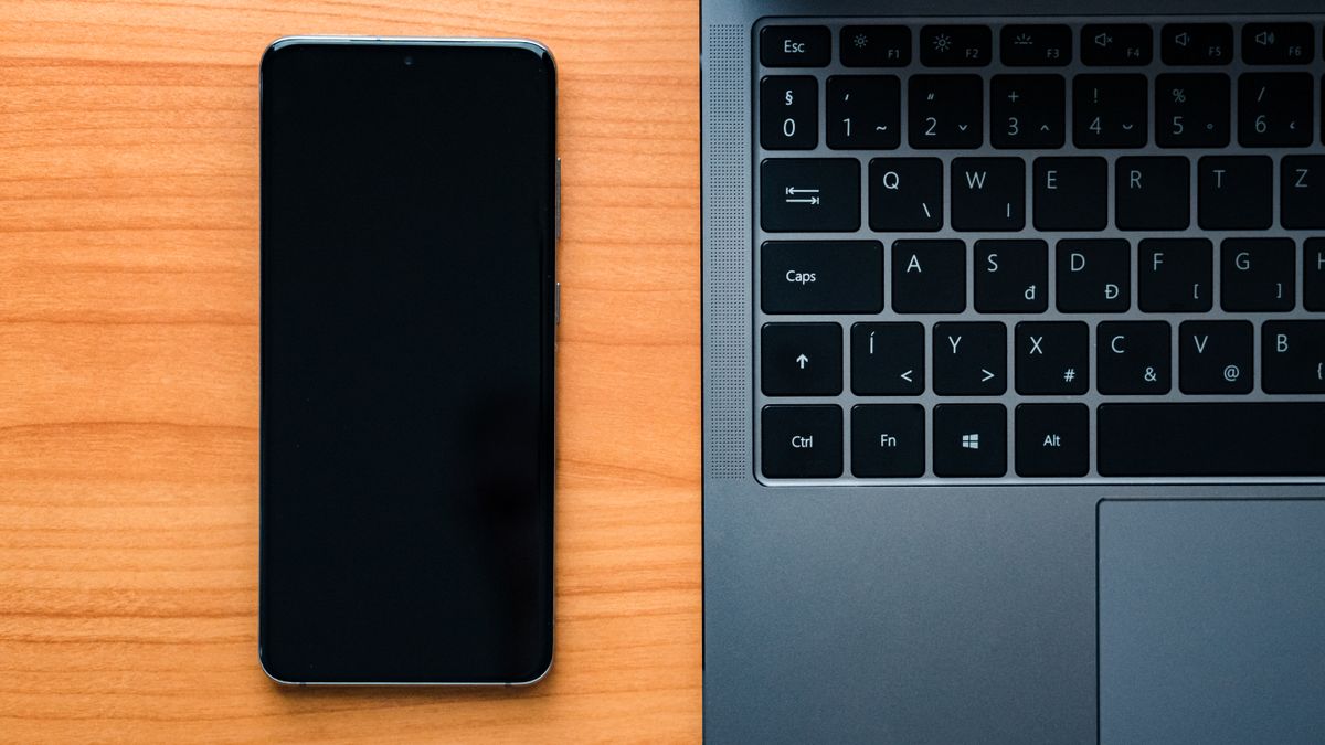 Flat lay of a laptop and smartphone on a wooden desk, perfect for technology themes.