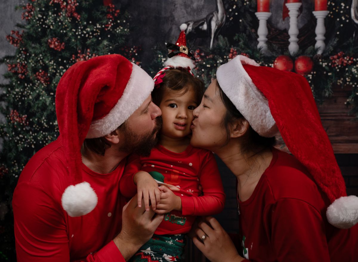 Happy family embraces holiday spirit with Santa hats and Christmas decor in a cozy indoor setting.