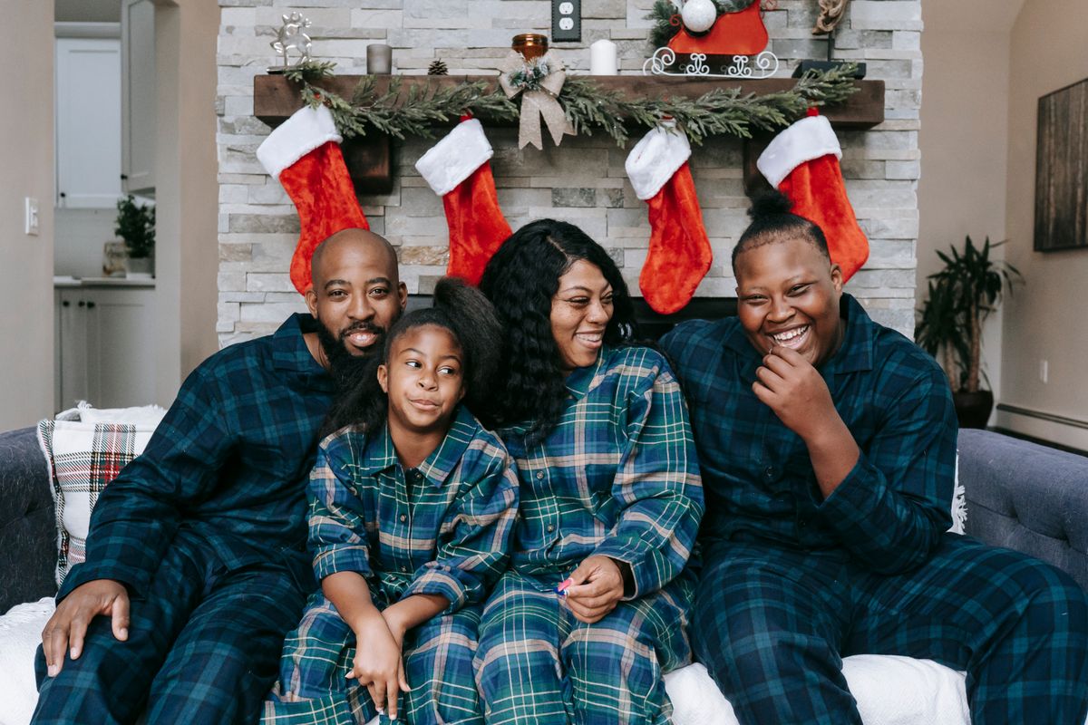 Family in matching pajamas enjoying Christmas together by the fireplace.