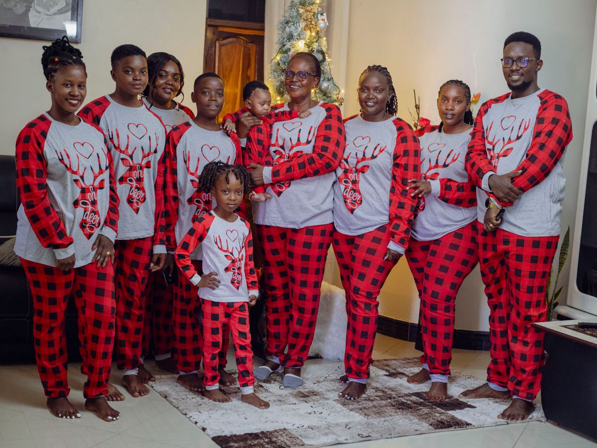 A happy family wears matching Christmas pajamas, gathered around a festive tree indoors.