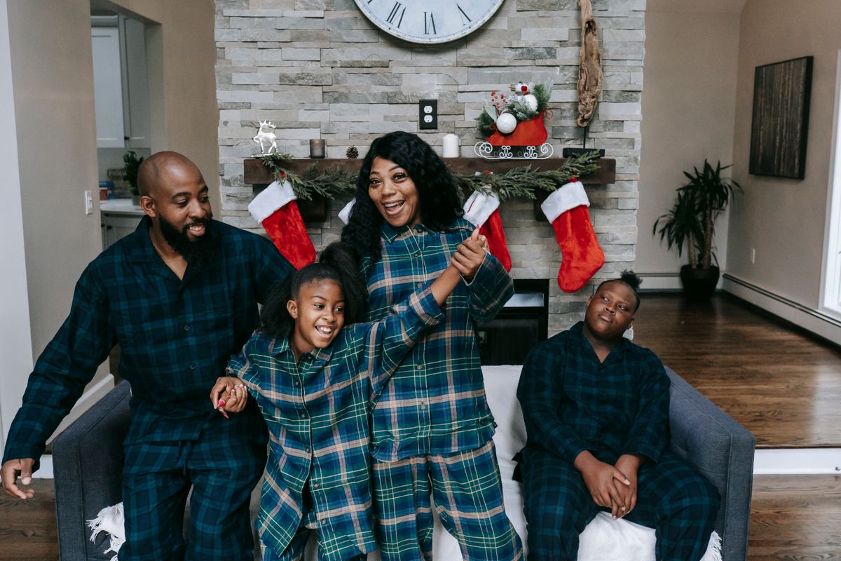 Cheerful African American family in same clothes gathering in cozy living room decorated with Christmas stockings