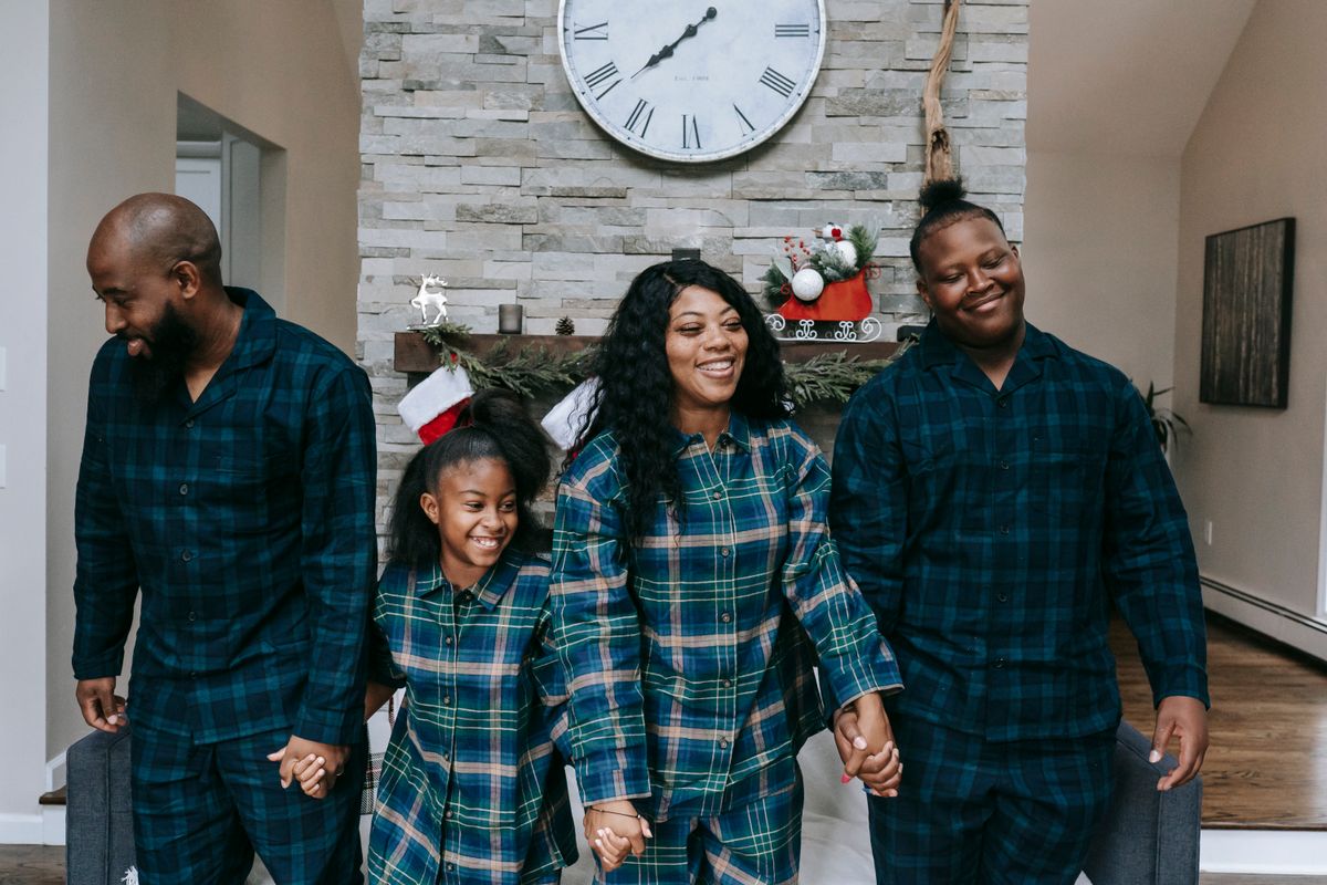 Happy African American family smiling happily while holding hands in living room with Christmas decorations