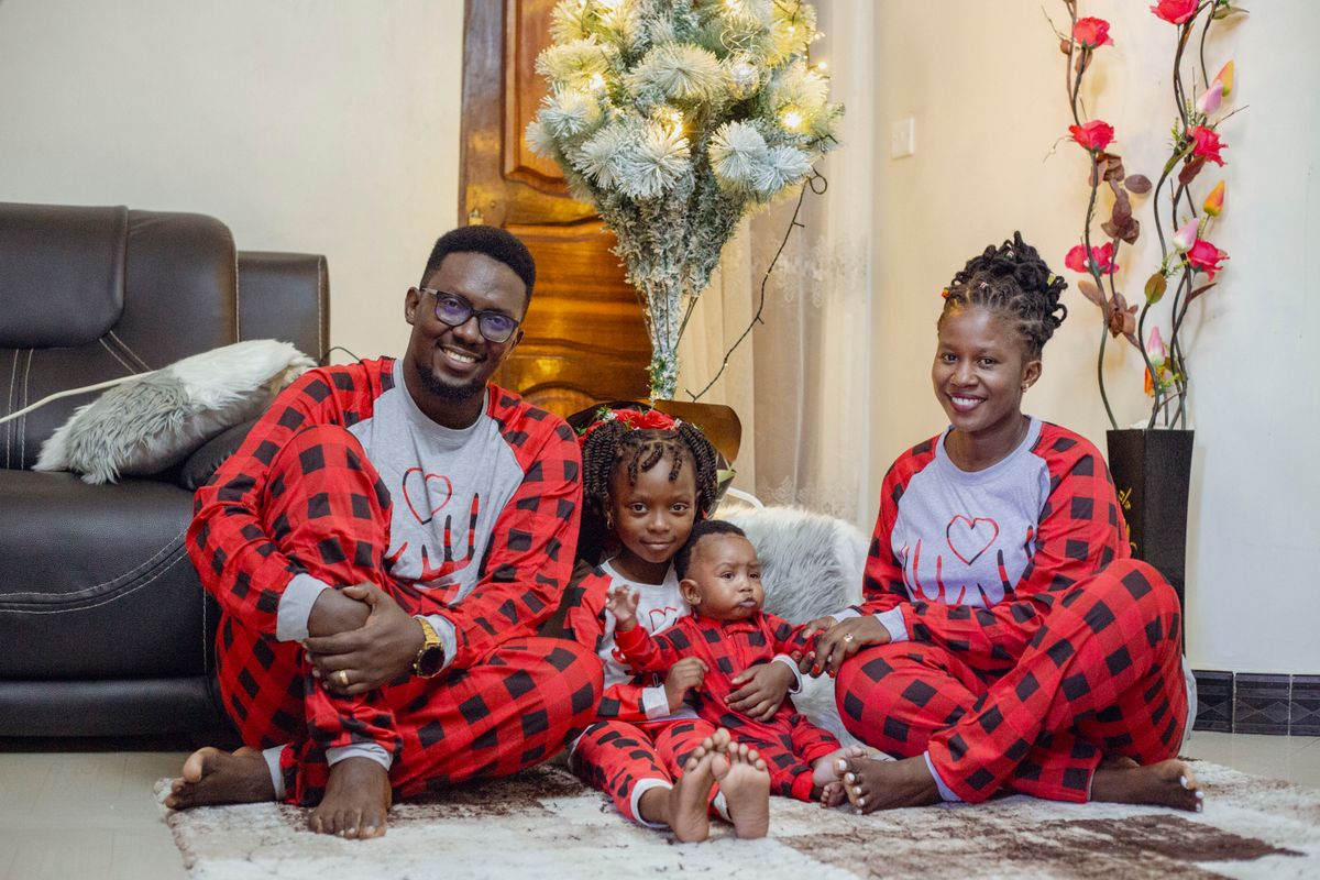 Happy family in matching plaid pajamas enjoying festive indoors setting with decor.
