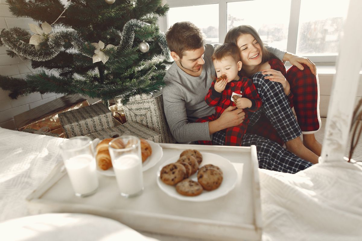 Cozy family moments by the Christmas tree, sharing cookies and milk on a winter morning.
