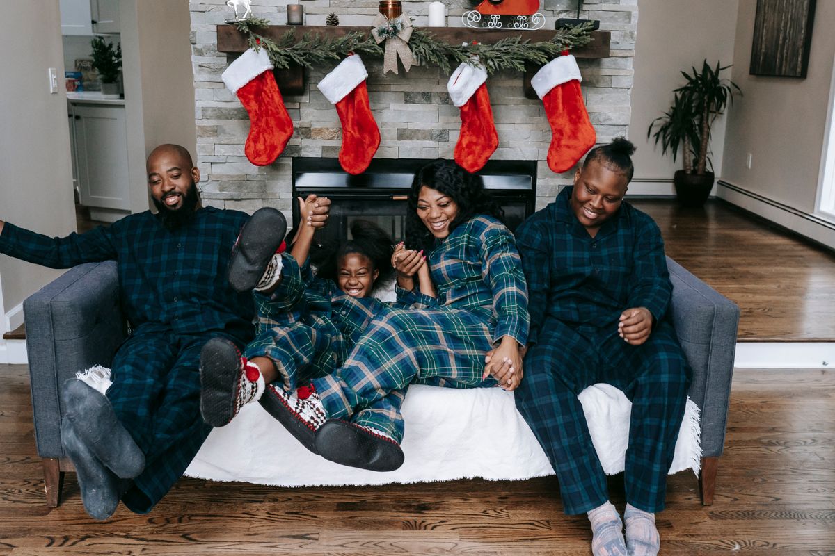 Full length of African American family laughing happily while celebrating Christmas Eve in decorated apartment