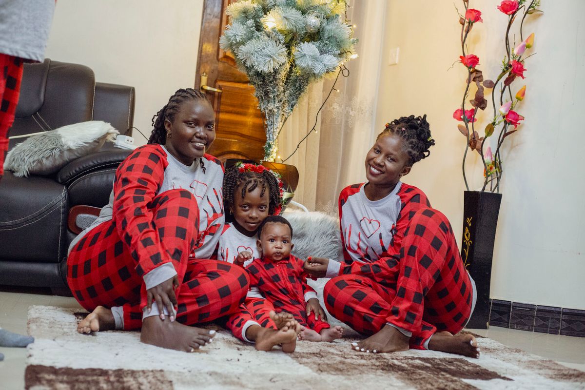 Family enjoying time together in matching pajamas by a Christmas tree indoors.