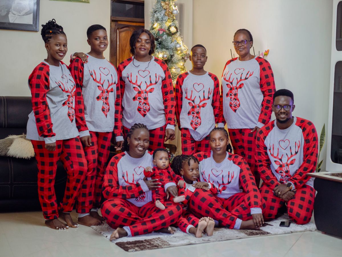 Family gathered in matching pajamas celebrating Christmas by a decorated tree indoors.